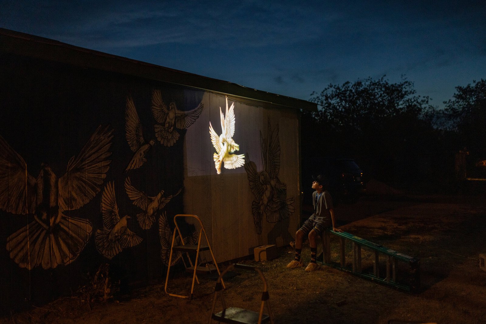 Matthew Villanueva, 10, of San Antonio, looks on as Michael Sanchez, a San Antonio artist, adjusts the placement of doves for a mural honoring the victims.